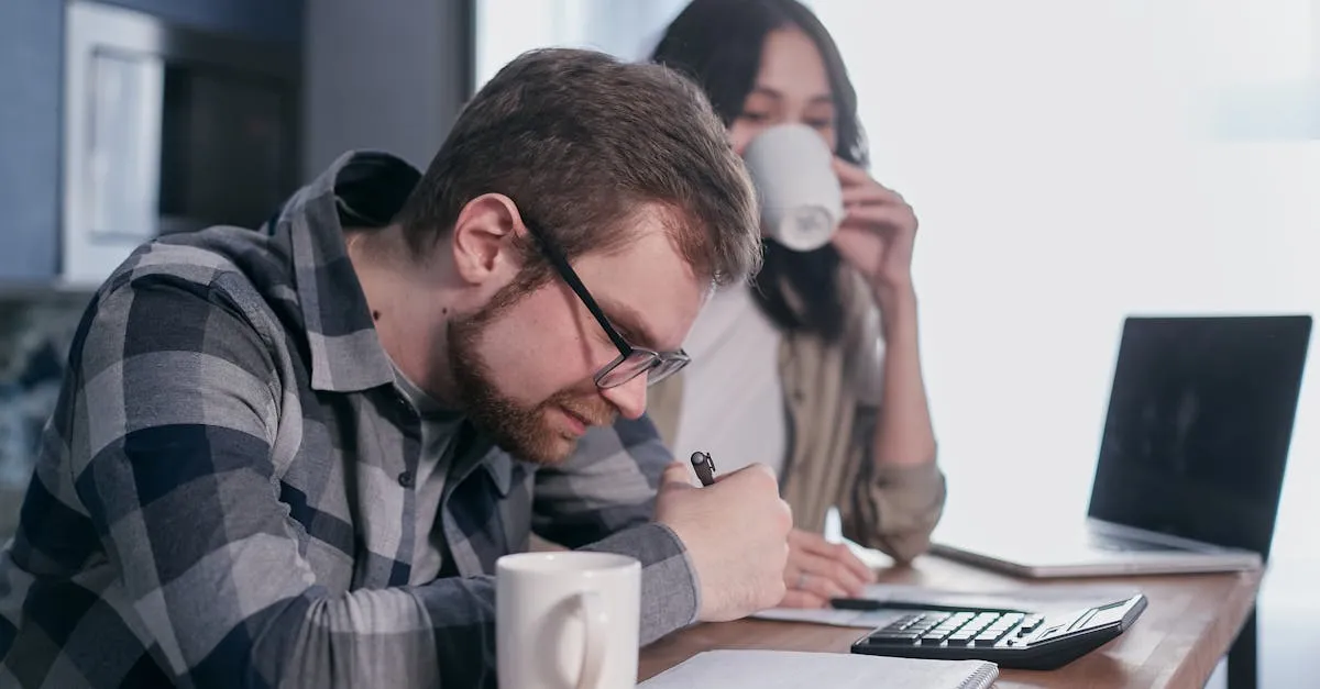 Homem escrevendo e mulher bebendo café enquanto trabalham em uma mesa com laptop e calculadora.
