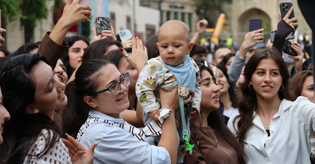 Grupo de pessoas sorrindo em um evento ao ar livre, com uma criança sendo segurada por uma mulher.