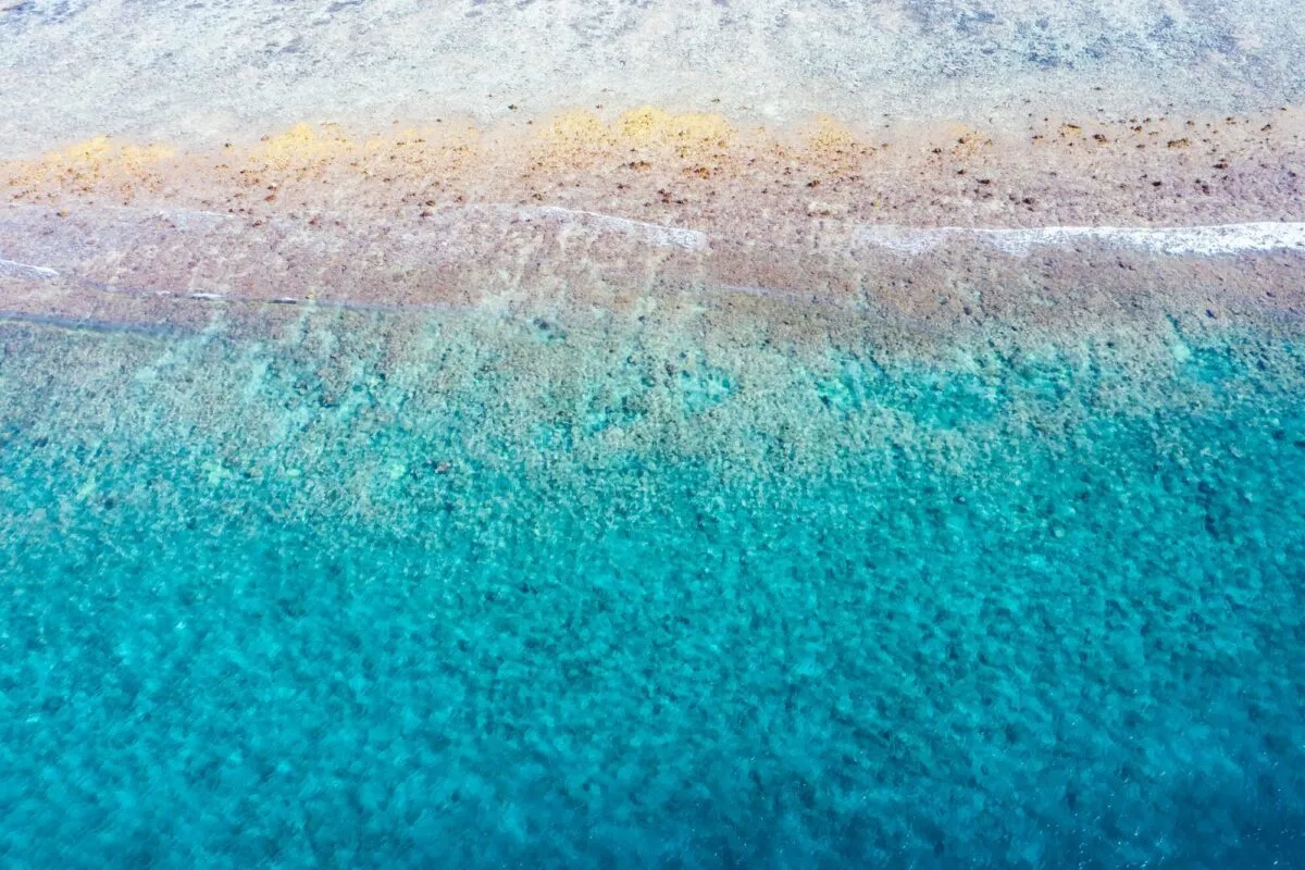 Vista aérea de águas rasas em tom turquesa sobre um recife de areia clara no oceano tropical