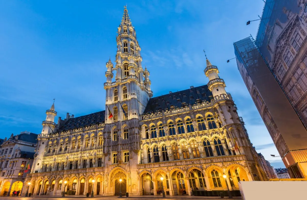 Fachada gótica da prefeitura de Bruxelas, na praça Grand Place, iluminada ao anoitecer sob o céu azul.