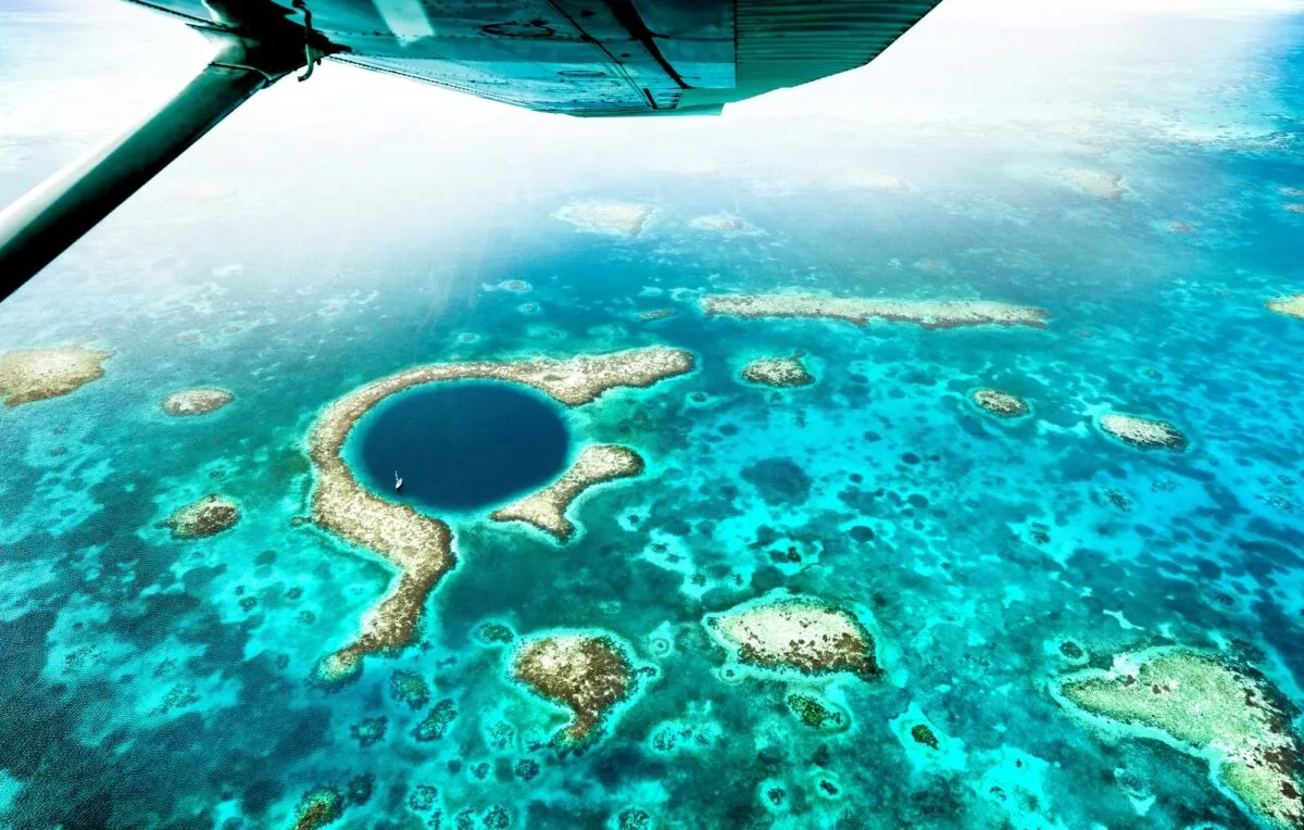 Vista aérea do Great Blue Hole, sumidouro azul-escuro circular cercado por recifes de corais e água turquesa em Belize