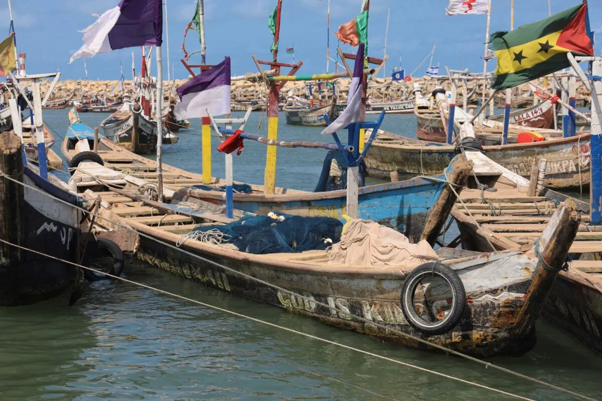 Barcos de pesca de madeira coloridos, com bandeiras, atracados no porto de Acra, capital de Gana