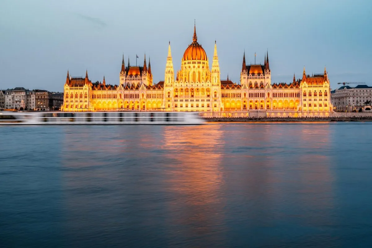 Edifício do Parlamento húngaro iluminado ao entardecer, refletido nas águas do rio Danúbio, em Budapeste