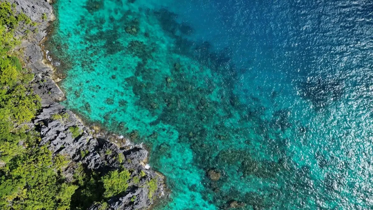 Vista aérea de litoral tropical das Filipinas, com mar azul-turquesa, recife de coral e falésias cobertas de vegetação