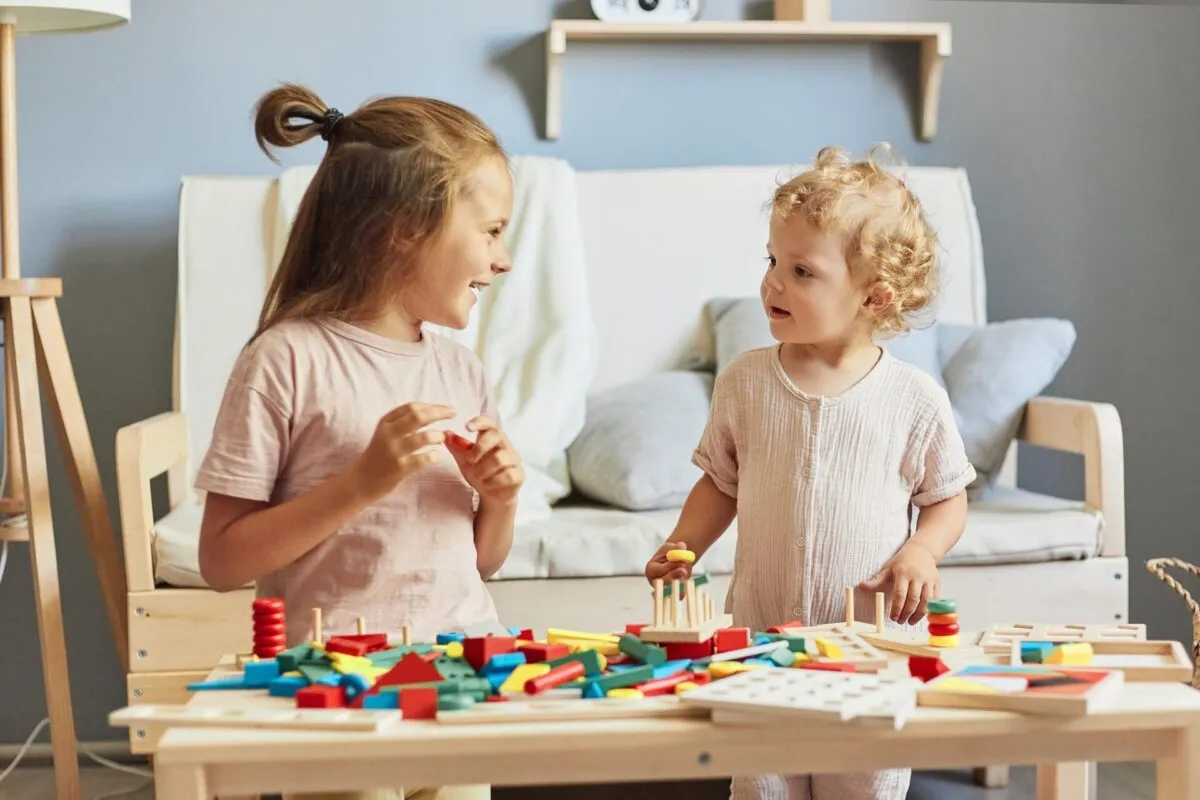 Duas crianças sorridentes interagindo com brinquedos educativos à mesa